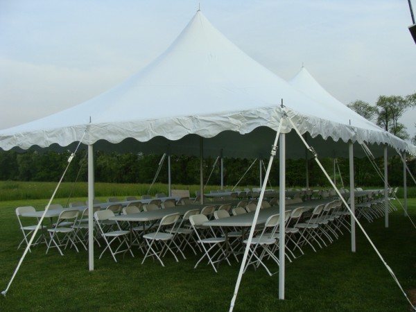 Large white party tent set with rows of tables and chairs