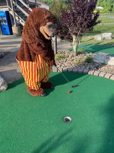 Billy Bob mascot lining up a putt on the outdoor miniature golf course