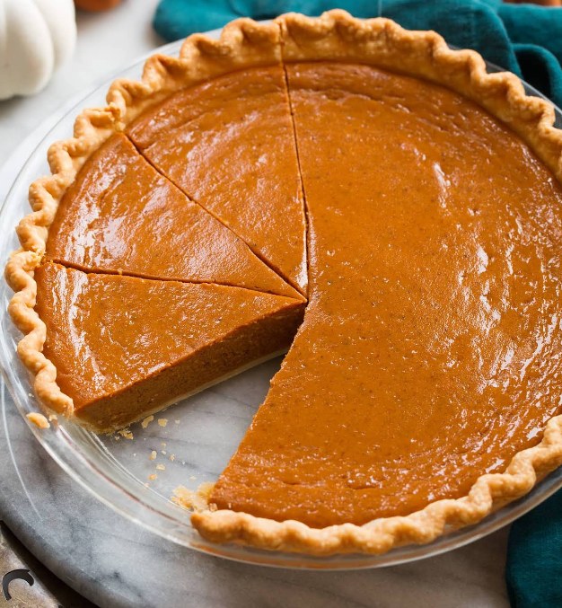 Freshly baked pumpkin pie with several slices cut